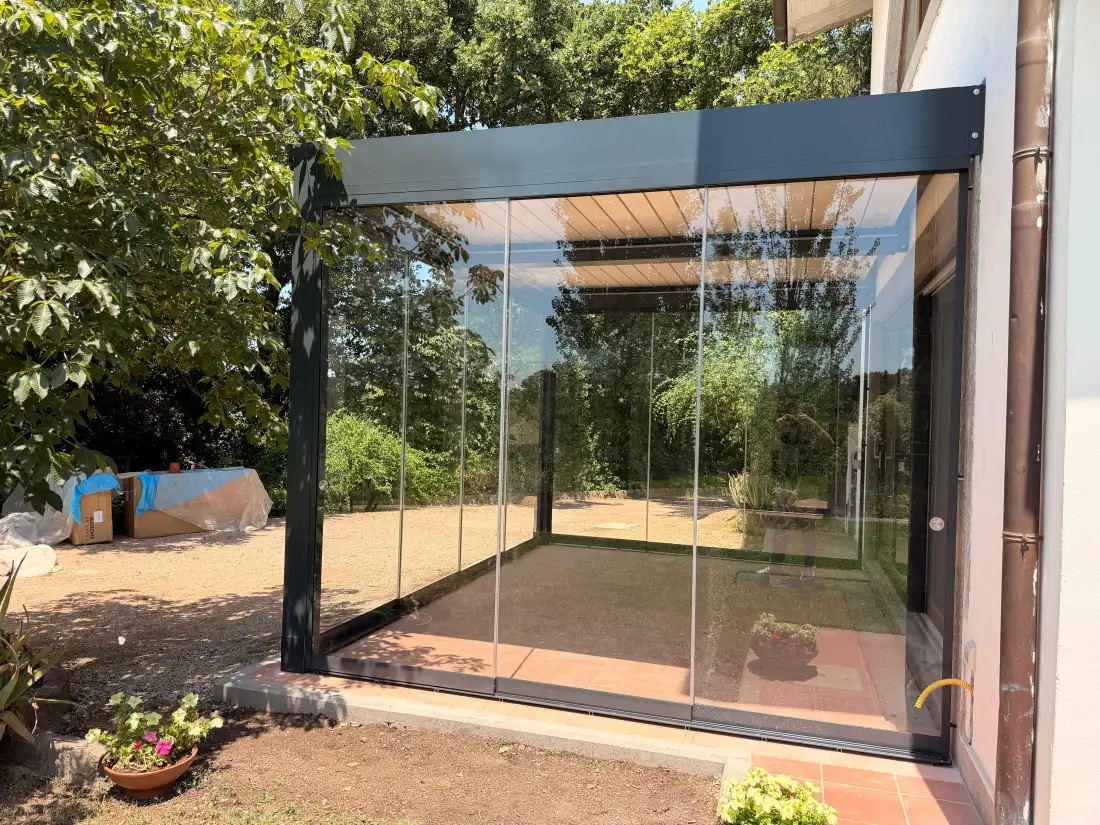 Veranda in vetro sotto una pergola bioclimatica, aperta sul giardino