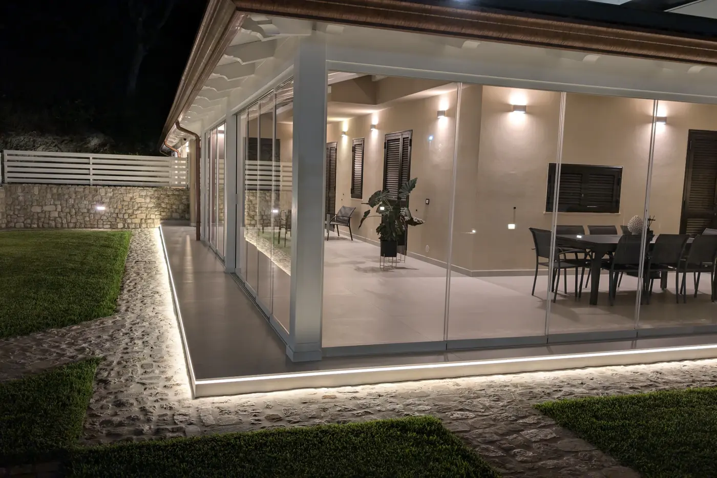 Veranda chiusa con vetrate scorrevoli Sliding Floor, illuminata di sera