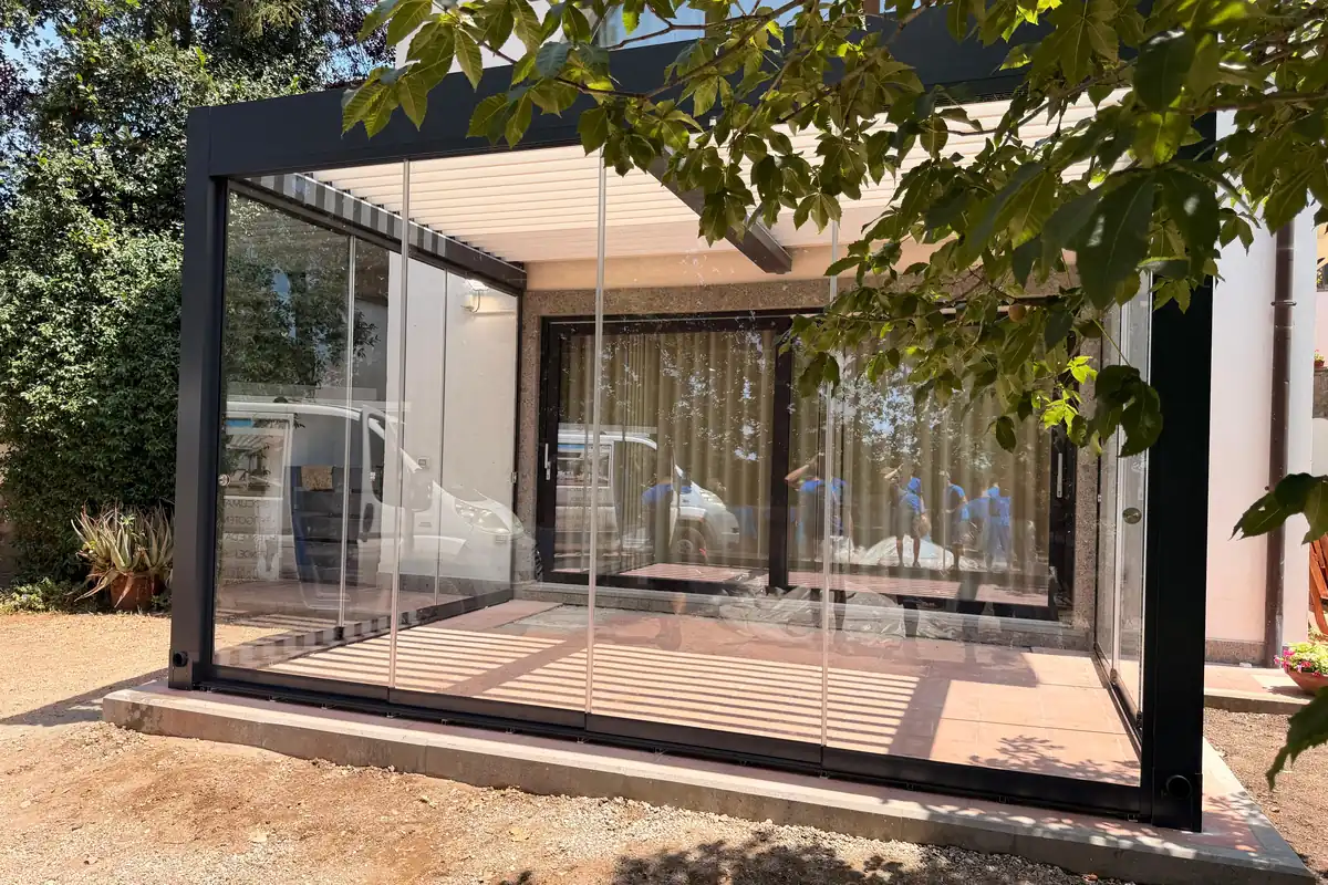 Pergola in alluminio con chiusure vetrate su tutti i lati, vista dal giardino