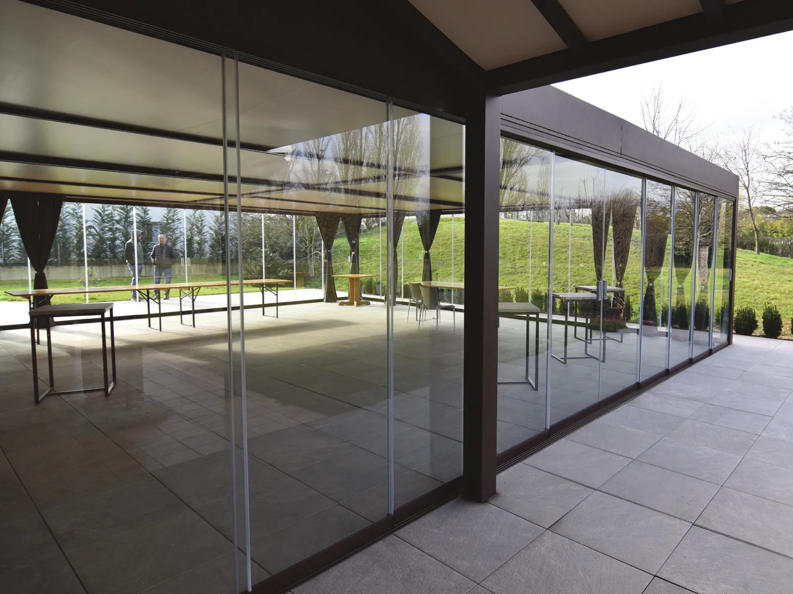 Interno del portico chiuso da Sliding Floor, con il parco visibile oltre i vetri